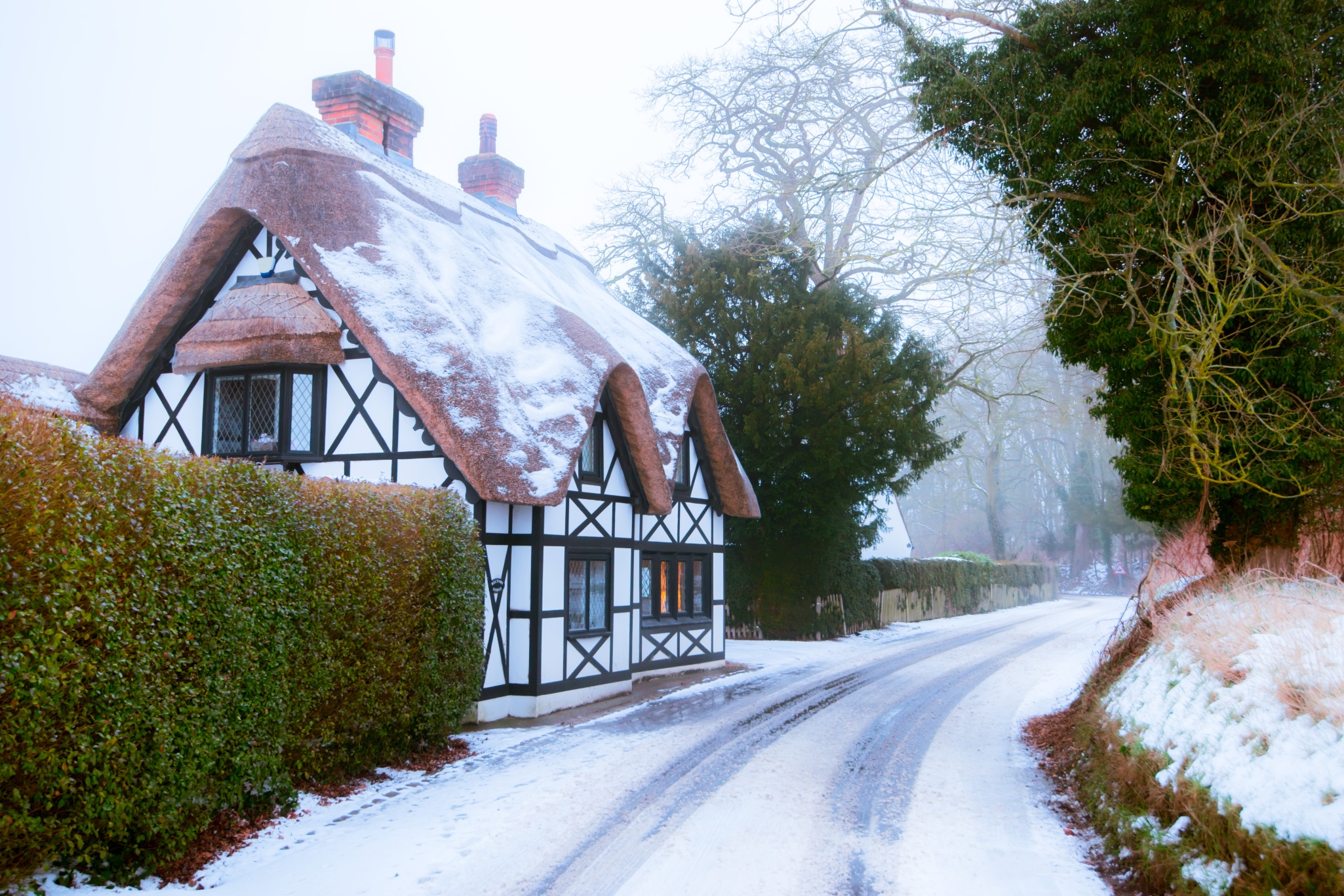 Snow-covered thatched timber frame cottage