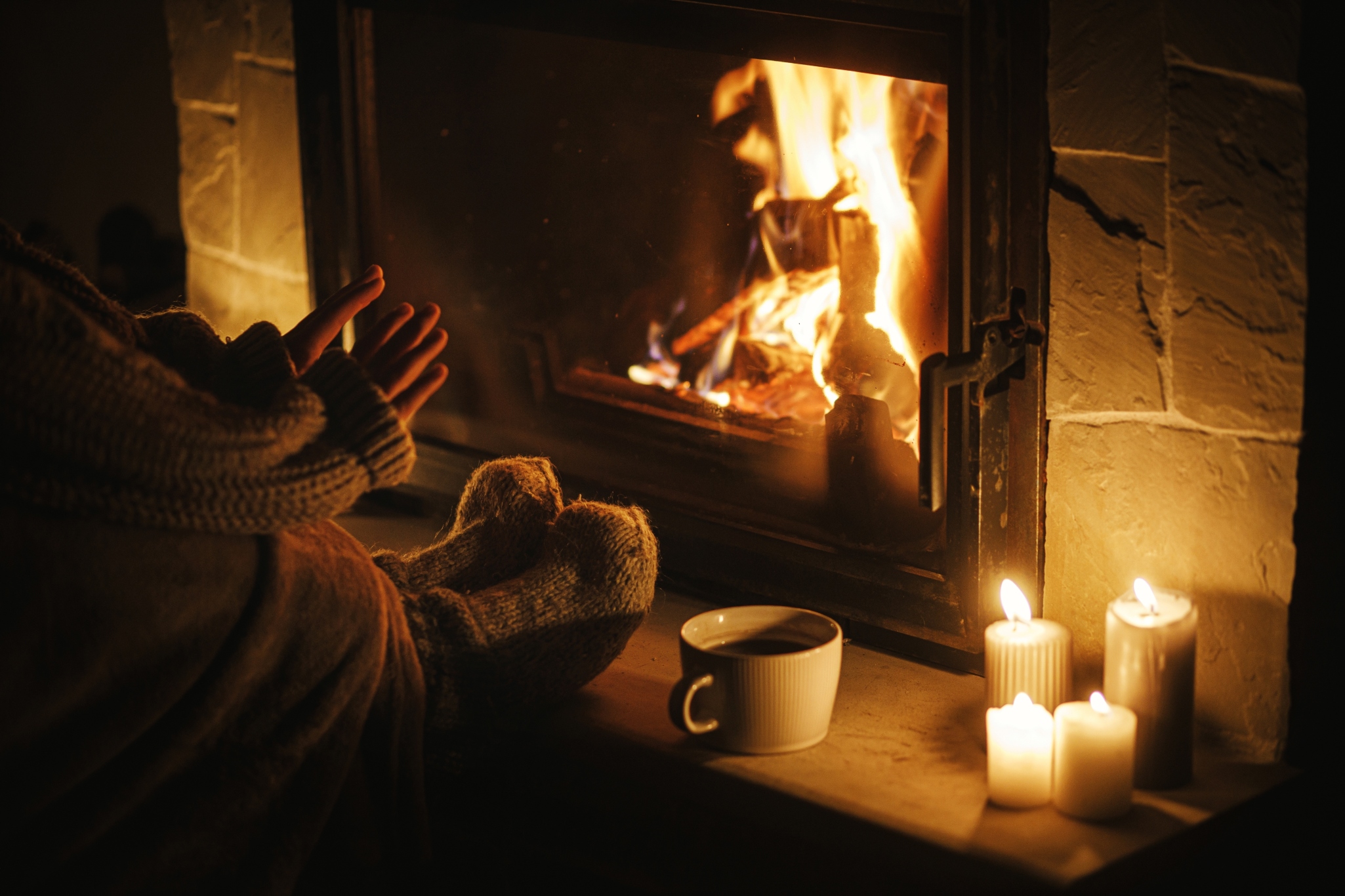 Woman warming hands by fire and candles
